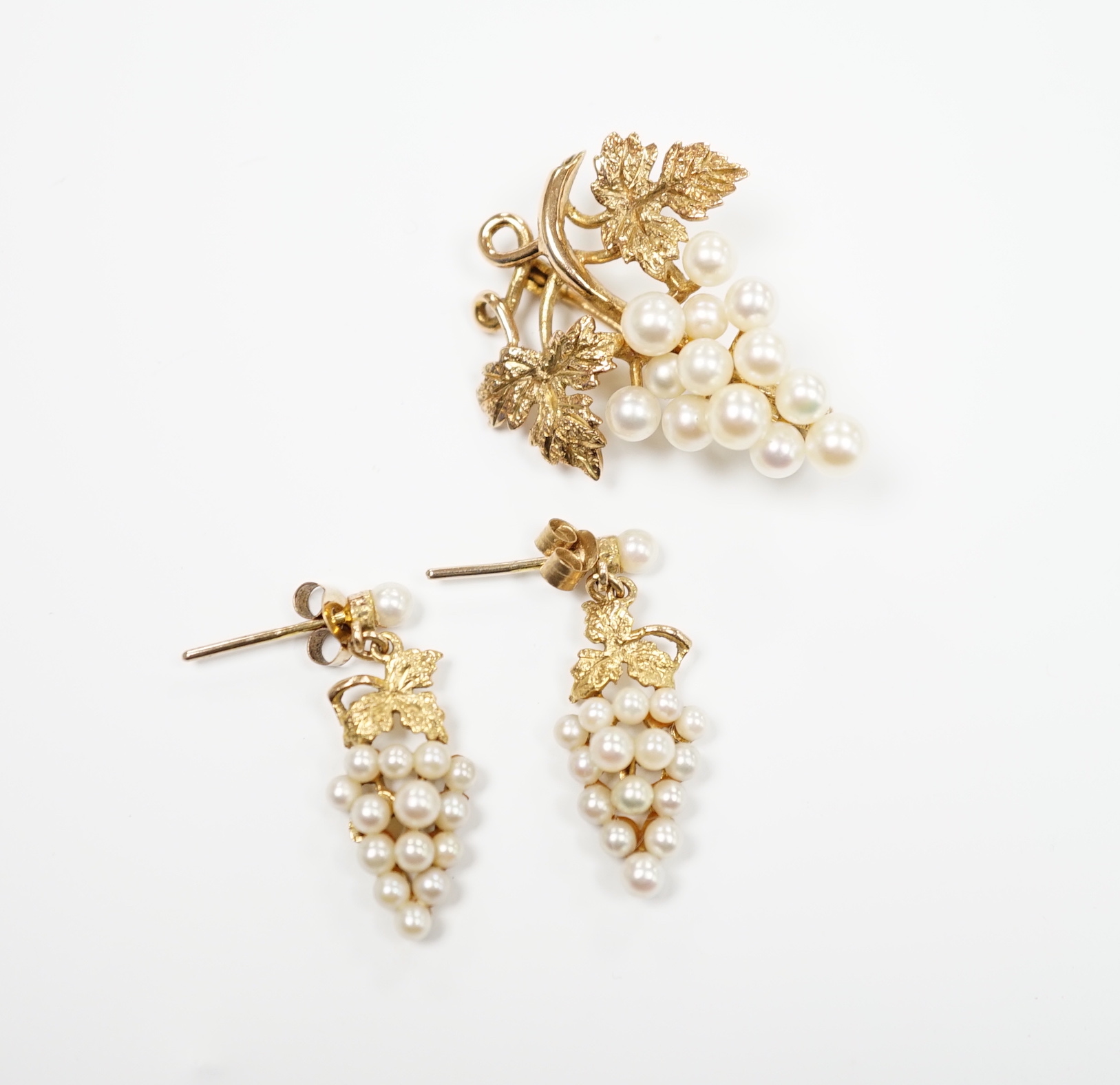 A modern 9ct gold and cultured pearl cluster set suite of jewellery, modelled as a bunch of grapes, comprising a brooch and pair of earrings, gross weight 7.3 grams.